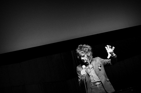 Jon Cooper Clarke on stage, mic in hand, declaiming