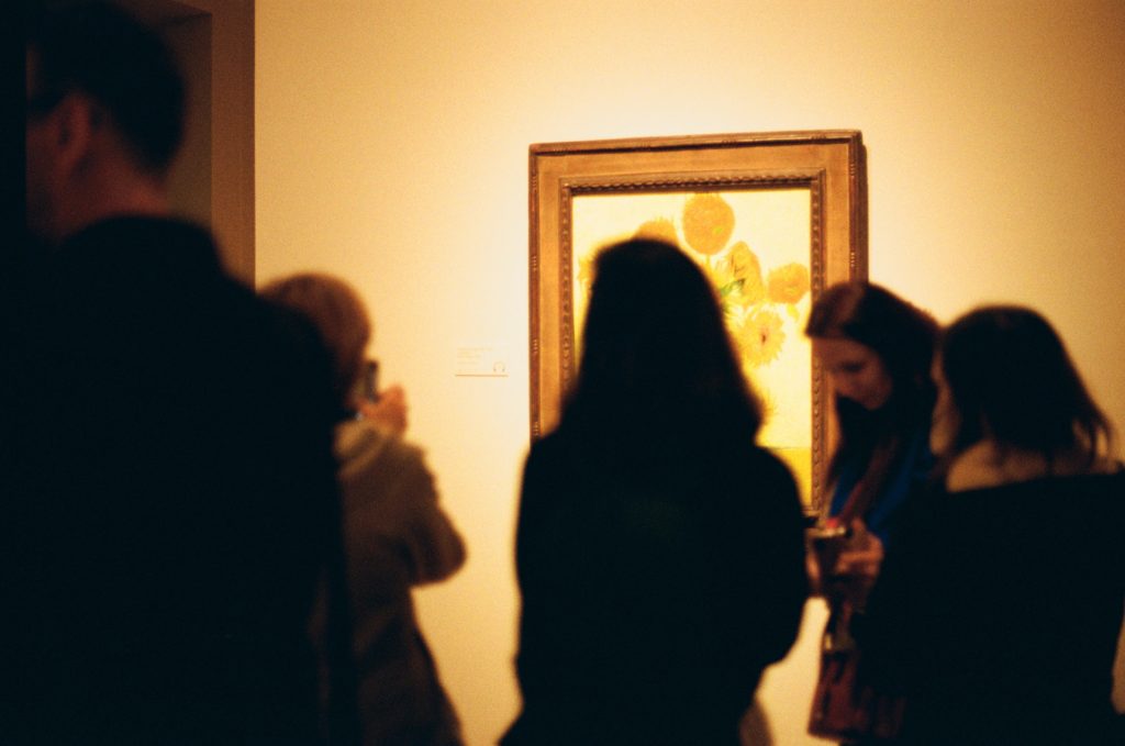 Vincent Vag Gogh's painting Sunflowers in a 2019 Tate Britain exhibition. Visitors to the gallery mill around in the foreground