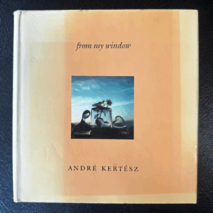 Front cover of a book of photos by Hungarian-American artist André Kertész. Glass ornaments on a windowsill refract the light from the New York sky beyond.